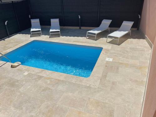 une piscine avec deux chaises et quelques chaises bleues dans l'établissement Villa avec Piscine privée proche mer, à La Garonnette-Plage
