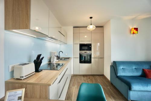 - une petite cuisine avec un canapé bleu dans une chambre dans l'établissement L'Escale, à La Forêt-Fouesnant