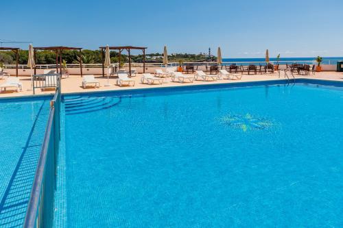 a large blue swimming pool with chairs and tables at Bellevue Belsana in Portocolom