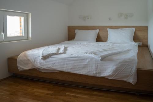 a large bed with white sheets and pillows at Apartmani Vinarije IN in Mionica