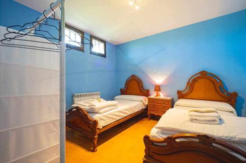 2 łóżka w pokoju z niebieskimi ścianami w obiekcie El Collao de Nuño w mieście Gijón