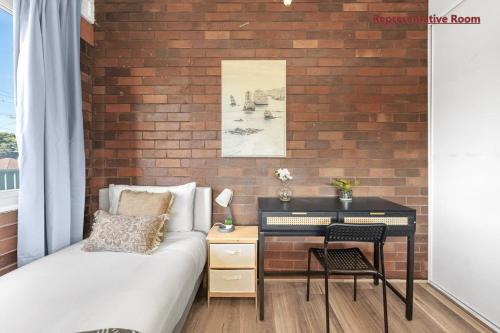 a bedroom with a brick wall with a bed and a desk at Comfort Single Room - Private - Prime Spot in Hurstville in Sydney