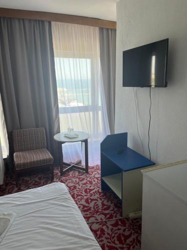 a hotel room with a bed and a tv and a chair at Hotel Banat in Olimp