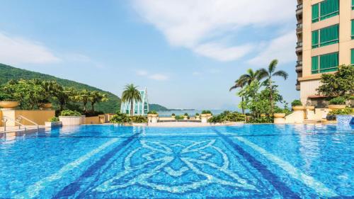 uma piscina num hotel com montanhas ao fundo em Auberge Discovery Bay Hong Kong em Hong Kong
