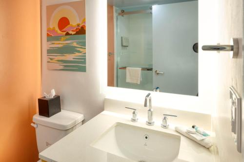 baño con lavabo y aseo con espejo en Golden Sands Oceanfront Hotel, en Carolina Beach