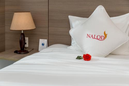 a white bed with a red rose on it at The Nalod Da Nang in Da Nang