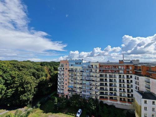 a tall apartment building with trees in the foreground at Apartament Słoneczny in Kołobrzeg