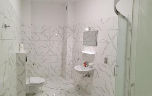 a white bathroom with a toilet and a sink at Apartamenty pod Jagodną in Spalona