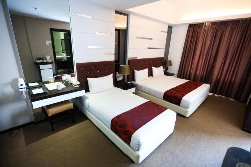 una camera d'albergo con due letti e una scrivania di Paradise Spa Hotel a Port Dickson