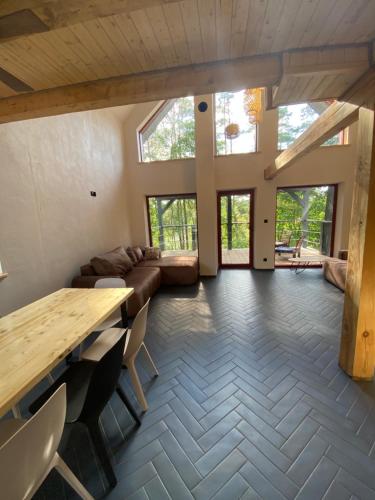 uma ampla sala de estar com uma mesa de madeira e cadeiras em Polana Gawrycha, domki nad jeziorem z widokiem em Suwałki