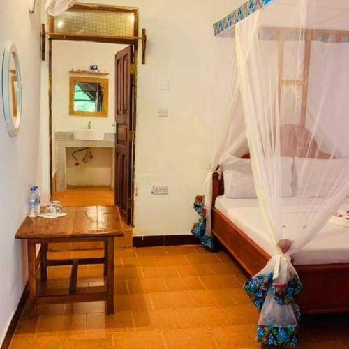 a bedroom with a bed and a table and a sink at Sipano Beach Lodge Kiwengwa in Kiwengwa