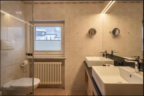 a bathroom with a sink and a toilet and a window at ARTEFUGIUM panoramico in Selva di Val Gardena