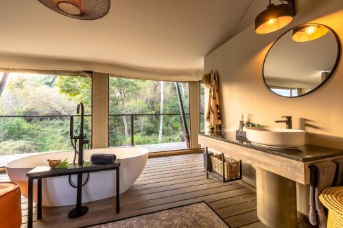 ein Badezimmer mit einer Badewanne, einem Waschbecken und einem Spiegel in der Unterkunft Mbizane Escarpment Retreat in Schoemanskloof