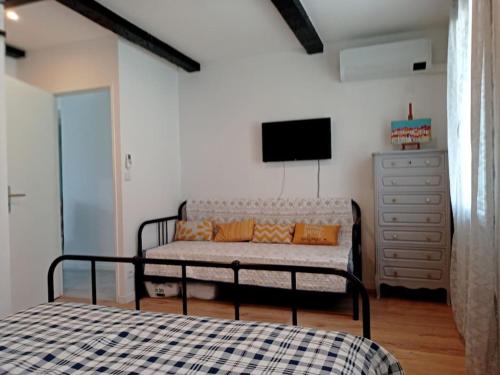- une chambre avec un lit, une télévision et une commode dans l'établissement Maison avec jardin, à Marseille