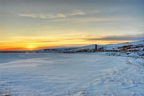 a field covered in snow with the sunset in the background at Gljúfurbústaðir Holiday Homes in Hveragerði