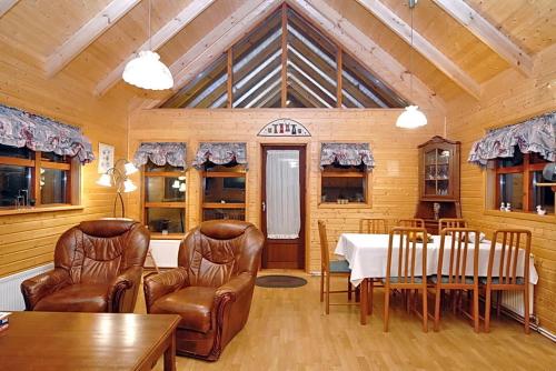a dining room with a table and leather chairs at Gljúfurbústaðir Holiday Homes in Hveragerði