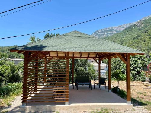 a wooden gazebo with a bench and a roof at Relax Apartmani in Sutomore