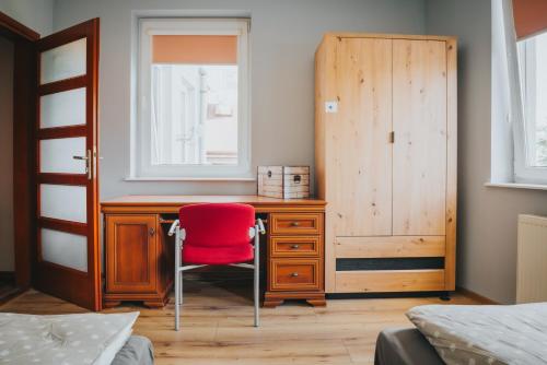 d'un bureau avec une chaise rouge à côté d'une fenêtre. dans l'établissement Apartament London, à Kielce