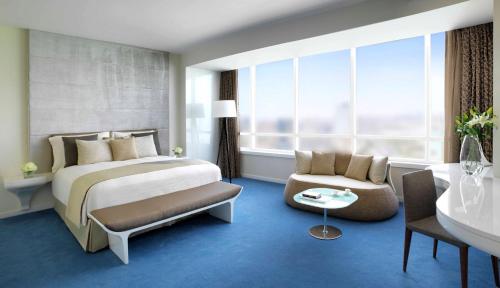 a bedroom with a bed and a chair and a sink at Symphony Style Hotel Kuwait in Kuwait