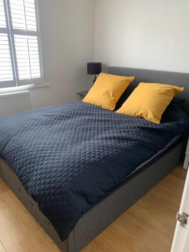 a bed with a blue comforter and yellow pillows at Beautiful Brighton Home in Brighton & Hove