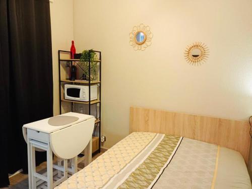 - une chambre avec un lit, une table et un four micro-ondes dans l'établissement Appartement calme et bien situé, à Tarbes