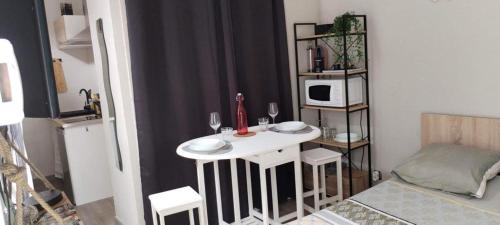 eine kleine Küche mit einem weißen Tisch und Stühlen in der Unterkunft Appartement calme et bien situé in Tarbes