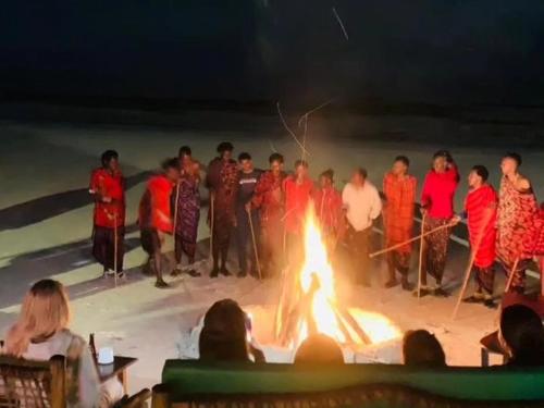 a group of people standing around a fire on the beach at Sipano Beach Lodge Kiwengwa in Kiwengwa
