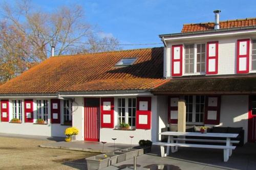 a red and white house with a bench in front at Hof ter Harte in Ypres