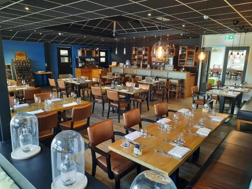 un comedor con mesas y sillas en un restaurante en Hotel De Schildkamp, en Asperen