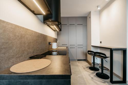 - une cuisine avec un comptoir et deux tabourets dans l'établissement Nocosfera Apartament Premium Ogrodowy I, à Kalisz