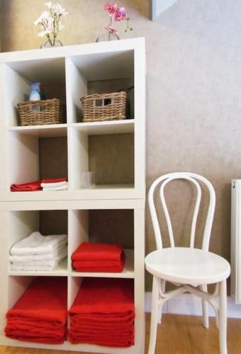a white book shelf with a chair and towels at Hof ter Harte in Ypres