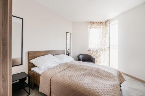 une chambre avec un lit, une chaise et une fenêtre dans l'établissement Nocosfera Apartament Premium Ogrodowy I, à Kalisz