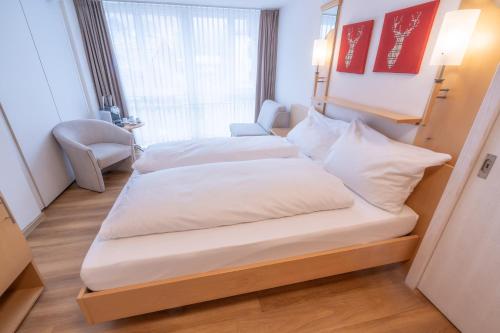 two beds in a small room with a window at Lifestyle & Spa Hotel Grächerhof in Grächen