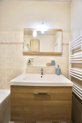 une salle de bain avec un lavabo et un miroir dans l'établissement L'Atoll *hyper centre*Parking*, à Concarneau