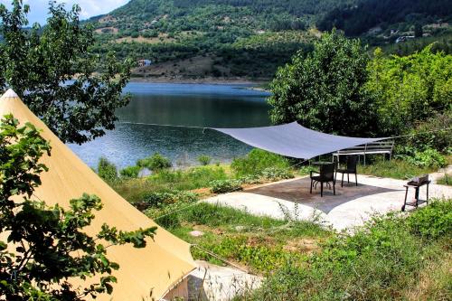 a tent with a table and chairs next to a lake at Lakeview Glamping in Staro Myasto