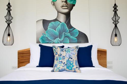 a bedroom with a painting above a bed with blue pillows at Zog Villas in Koh Samui 