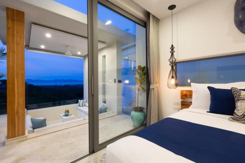 a bedroom with a large window and a bed with blue pillows at Zog Villas in Koh Samui 