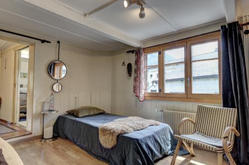 a bedroom with a bed and a chair and a window at Chalet Nostalgie in Chateau-d'Oex