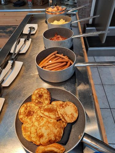 a table topped with pans of food and carrots at Hotel De Schildkamp in Asperen