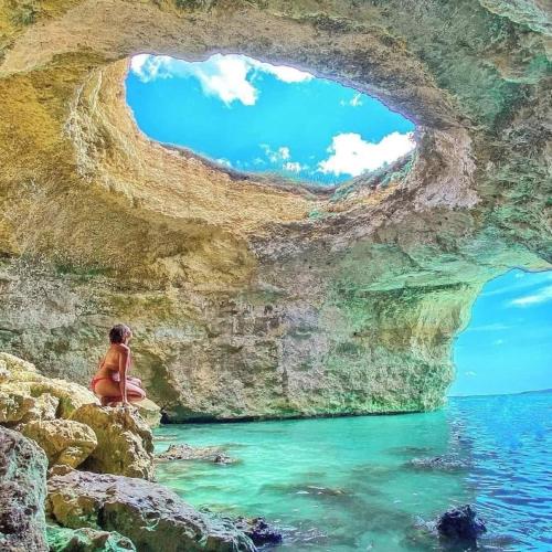 a person sitting on a rock in front of a cave at Chiardiluna in Castro di Lecce