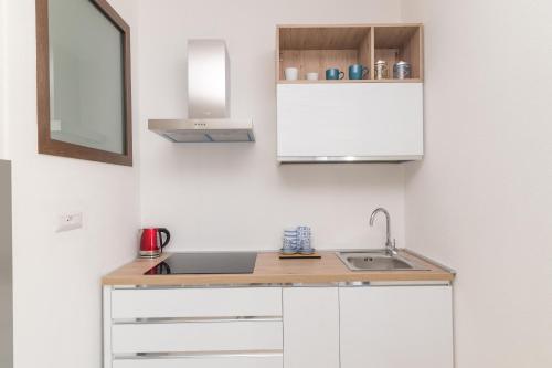 a kitchen with white cabinets and a sink at Appartamento Rosmarino In The City Center - Happy Rentals in Santa Teresa Gallura