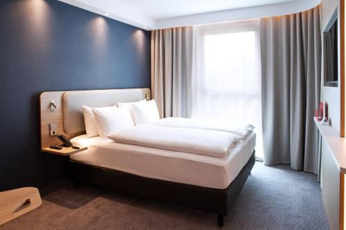 a bedroom with a bed with white sheets and a window at Holiday Inn Express Bochum, an IHG Hotel in Bochum