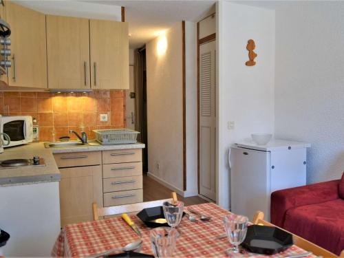 une petite cuisine avec une table et un canapé rouge dans l'établissement Studio coin montagne calme, 4 pers, parking, Risoul 1850 - FR-1-330-92, à Risoul
