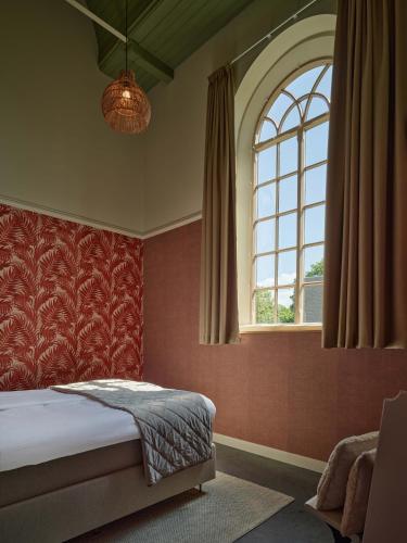 a bedroom with a bed and a large window at Kerkhotel Bij De Pastorie in Reitsum