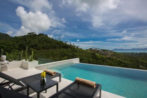 a swimming pool with two chairs and a table at Zog Villas in Koh Samui 
