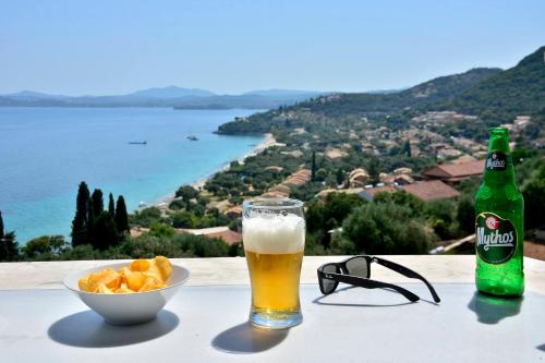 a glass of beer and a bowl of food and a bottle of beer at Ionia Living in Barbati