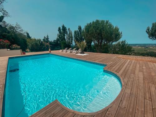 a swimming pool with a wooden deck and a swimming poolvisor at Villa Monbazillac, vue exceptionnelle, piscine, jacuzzi 10-16 pax in Monbazillac