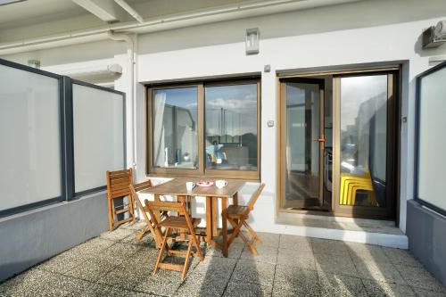 d'une table et de chaises en bois sur un balcon avec fenêtres. dans l'établissement Heol * plage à 100m*, à Larmor-Plage