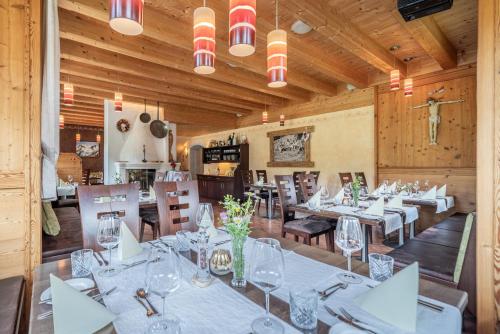 a restaurant with white tables and chairs and wooden walls at Der Ortnerhof - Hotel & Reiterhof in Prägraten am Großvenediger