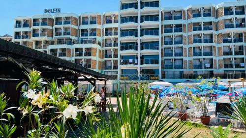 un hotel con una playa con sombrillas y un edificio en Hotel Delfin - All Inclusive, en Sunny Beach